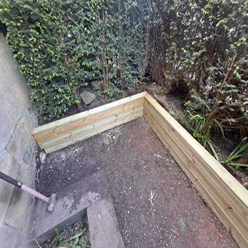 image of Indian Sandstone being laid with Decking Board used as a Planter / Border, this is a before image as part of an image slider